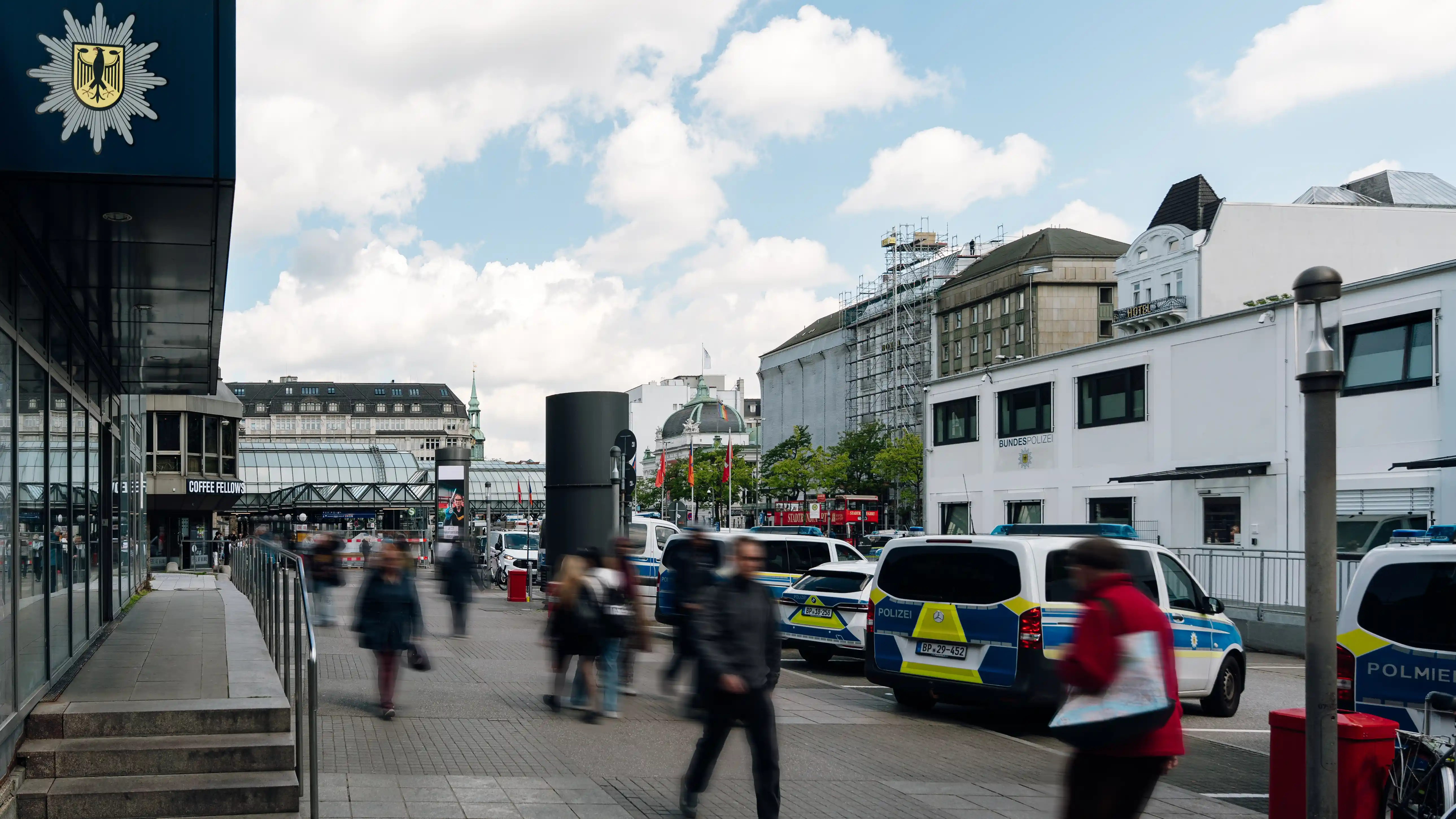 Bundespolizei-Fahrzeuge vor einem Gebäude der Bundespolizei in einer belebten Innenstadt mit Passanten.