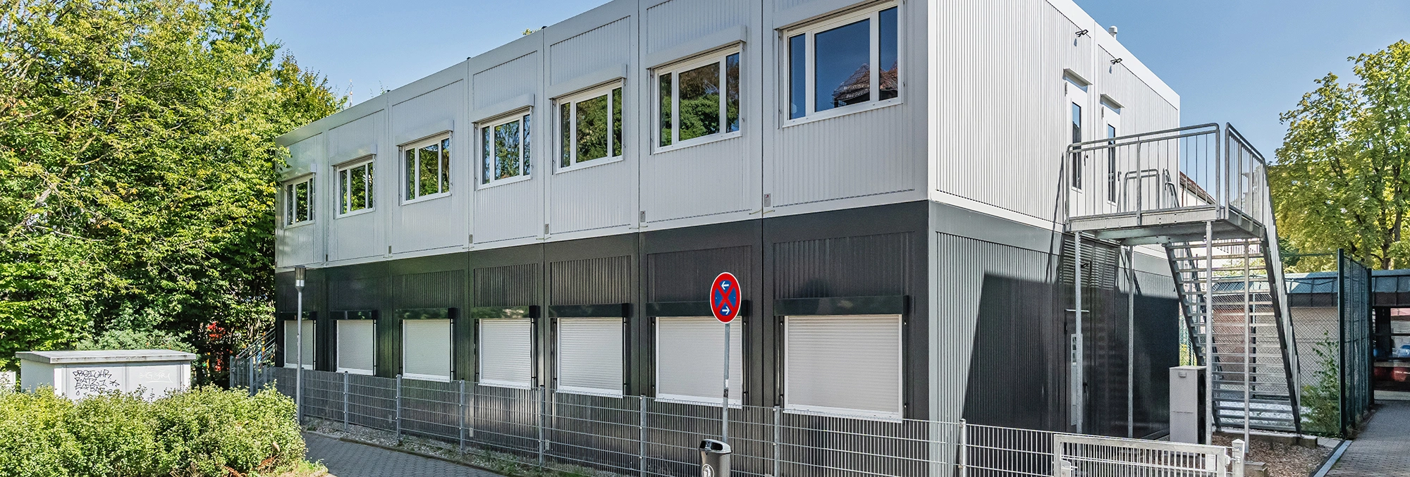 Zweigeschossiges Schulgebäude in Containerbauweise mit heller und dunkler Fassade