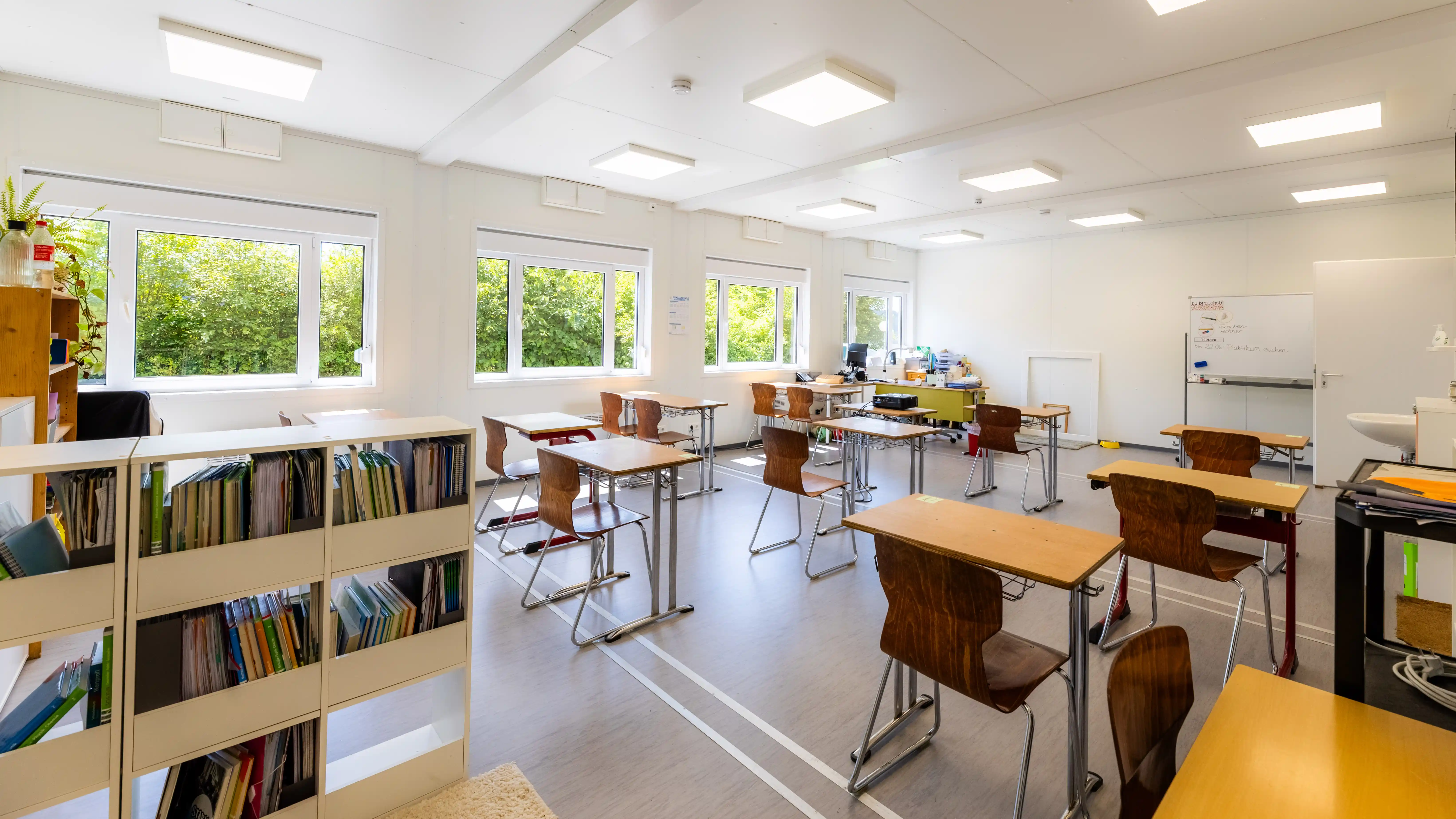 Heller Klassenraum in der temporären Schulcontaineranlage der Pestalozzi-Schule in Kronach. Große Fenster, moderne Beleuchtung und flexibel angeordnete Schülertische schaffen eine angenehme Lernumgebung.